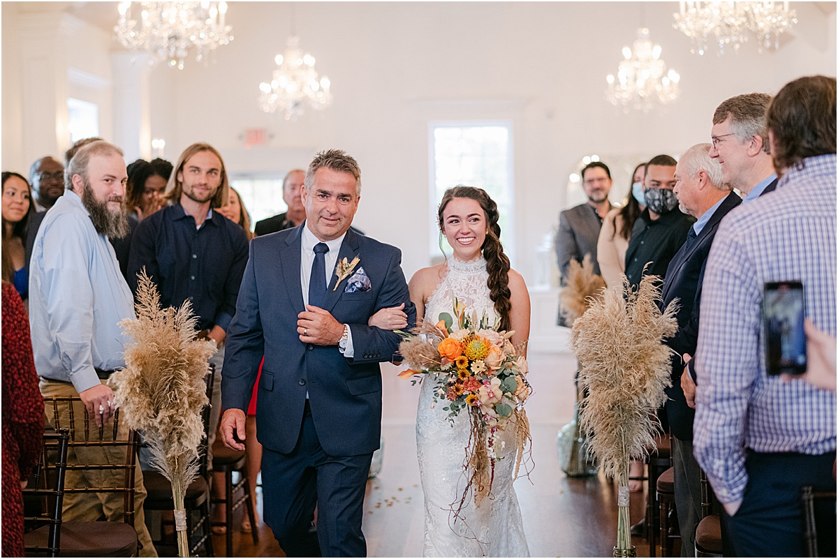 father of the bride walking his daughter down the aisle at the white room