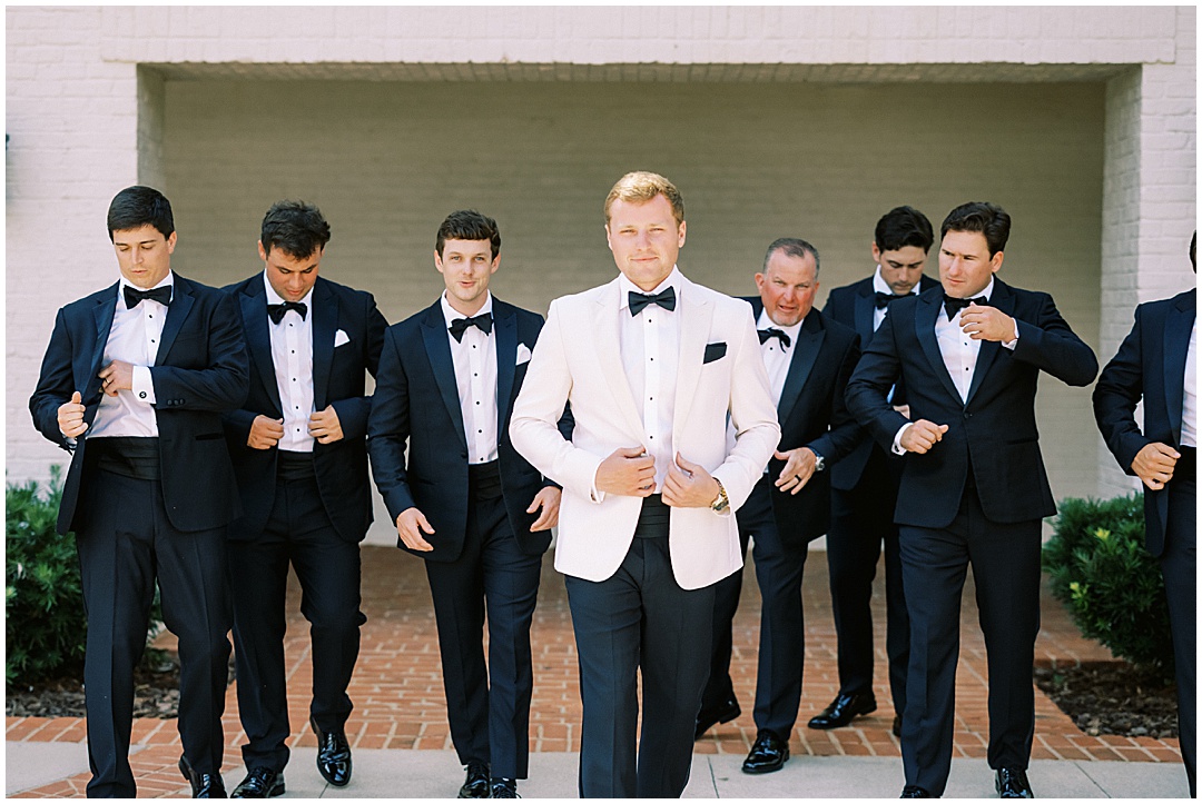 groom white tux and groomsmen black tux