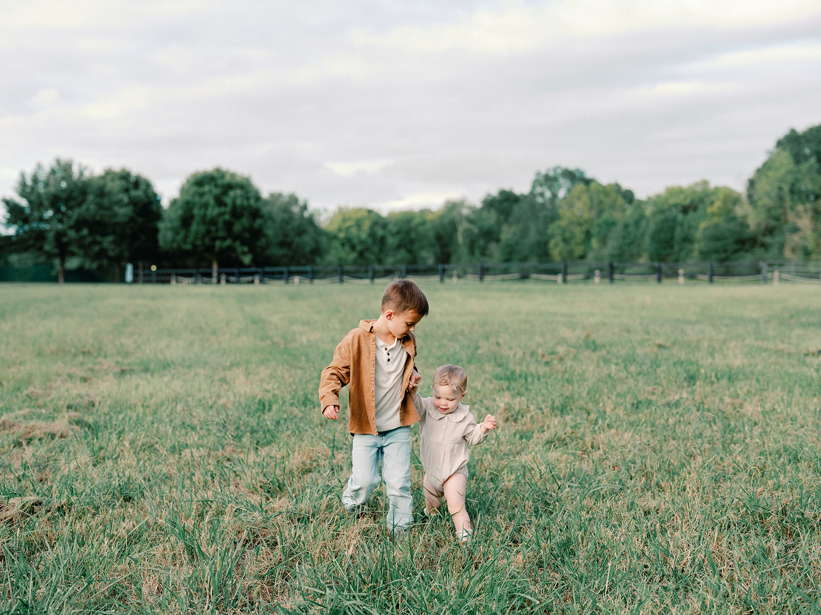 Fall Family Photos Atlanta - Mini Sessions - family photos atlanta Toddler Siblings Holding Hands Walking Through Field During Fall Family Photoshoot